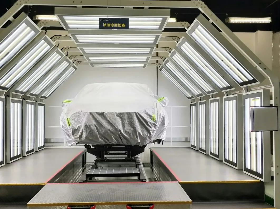 the detailing studio with a car under bright overhead light panels, wide