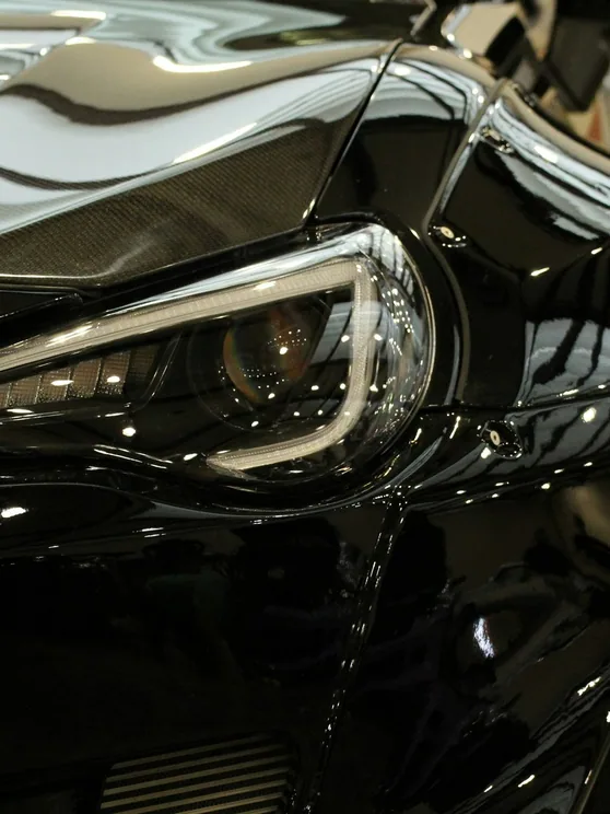 glossy black bonnet with studio light lines reflected in it, close, upright