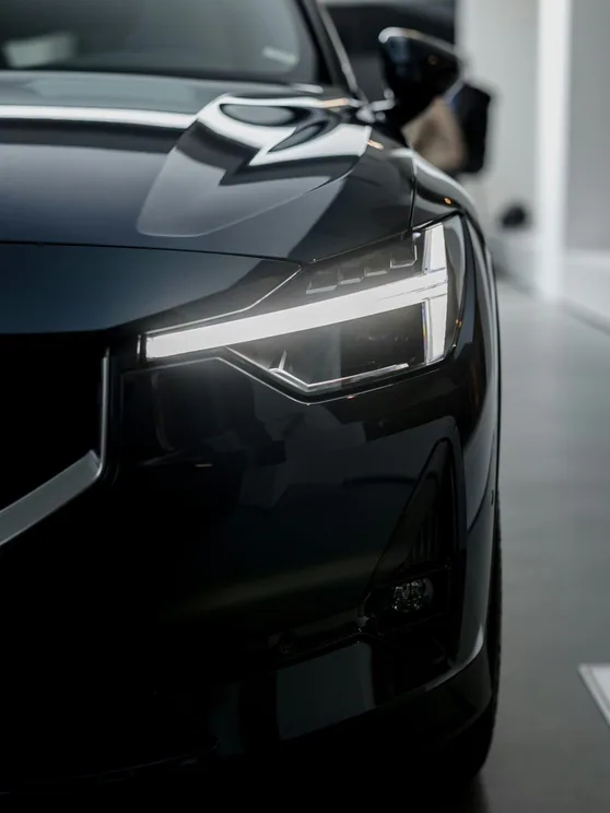 headlight and front wing of a freshly corrected dark car, studio light