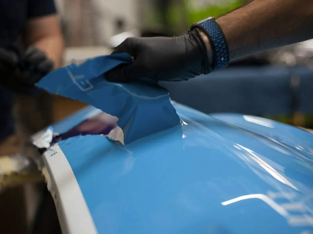 paint protection film being squeegeed onto a panel, gloved hands